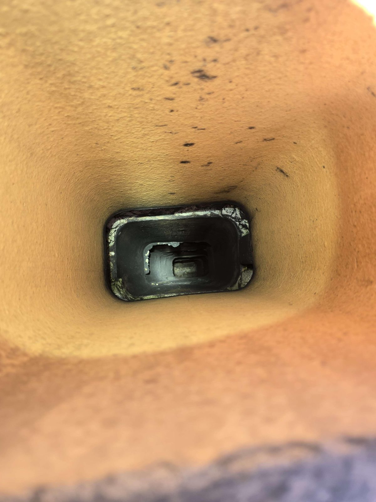 Top of a masonry chimney viewed from the roof, showing an open flue termination with no rain cap, and visible clay liner tiles offset at their joints inside the flue opening