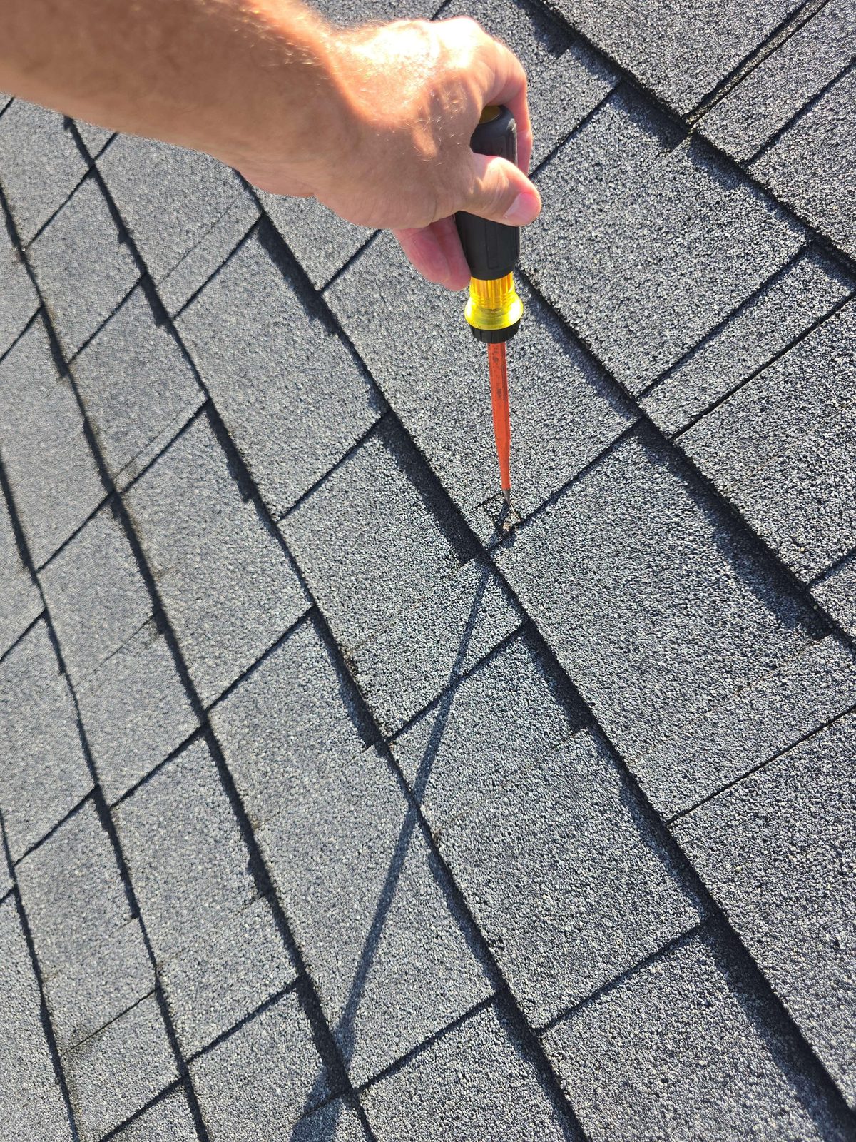 Close-up of architectural shingles on a roof showing visible cuts or slices across the shingle surface