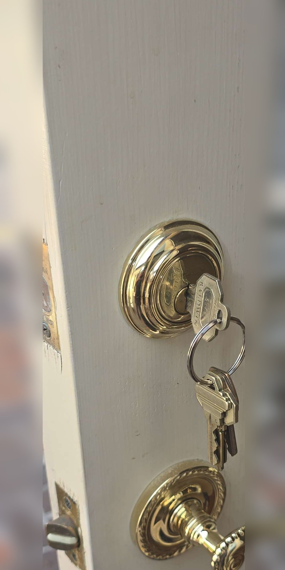 Exterior door edge with a double-keyed deadbolt, keys hanging from the interior cylinder