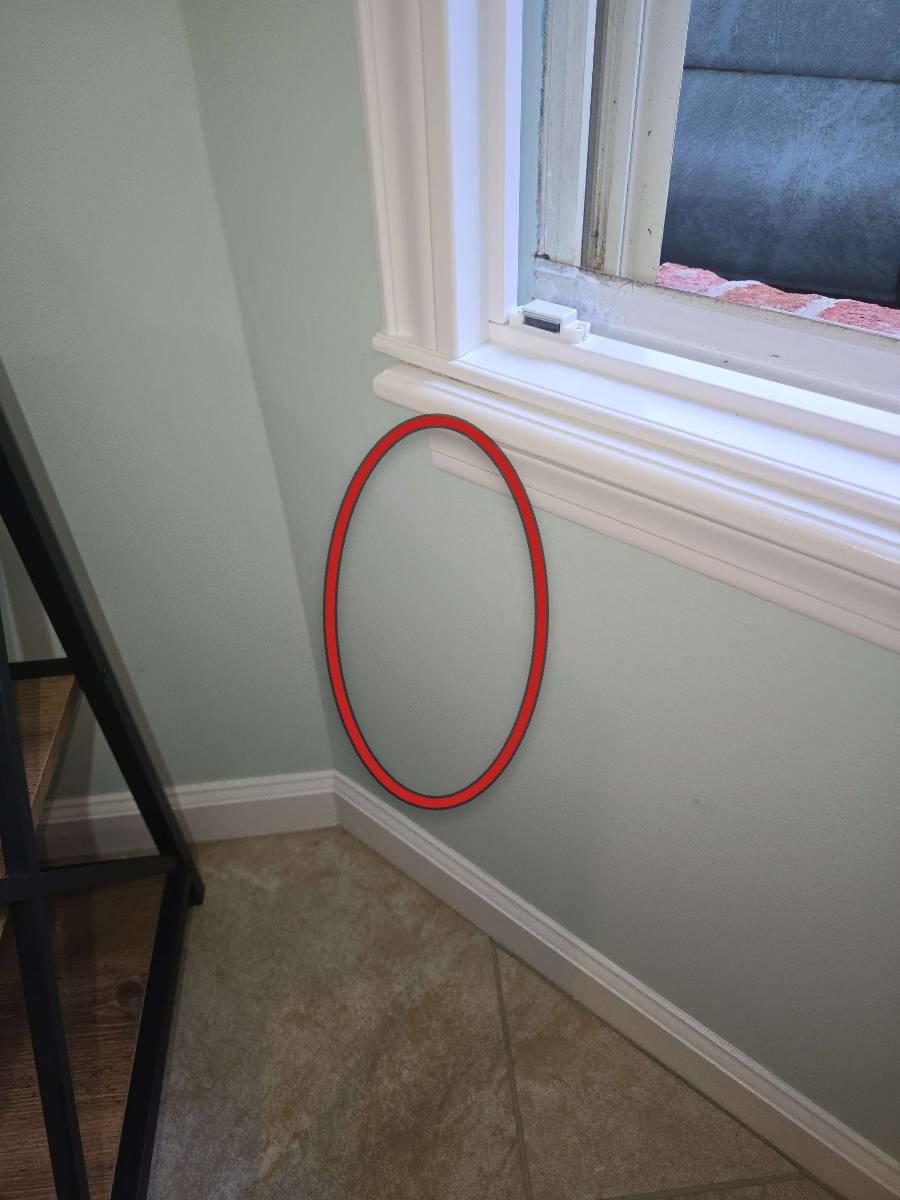 Close-up of cracked mortar joints in a brick veneer wall just above a window frame, with a visible bead of old caulk along the side and bottom of the window surround.