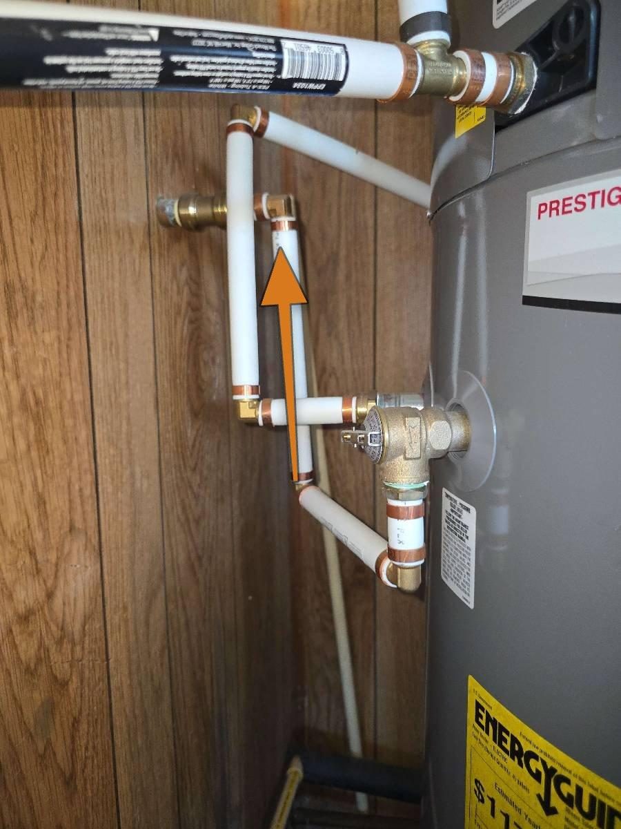 A section of pipe connected to the outlet of a water heater temperature and pressure relief valve, visibly rising upward before continuing toward its termination point.